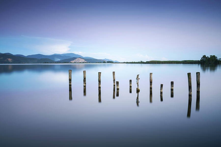 Wooden pier or jetty remains on a blue lake sunset and sky refle #3 Photograph by Stefano Orazzini