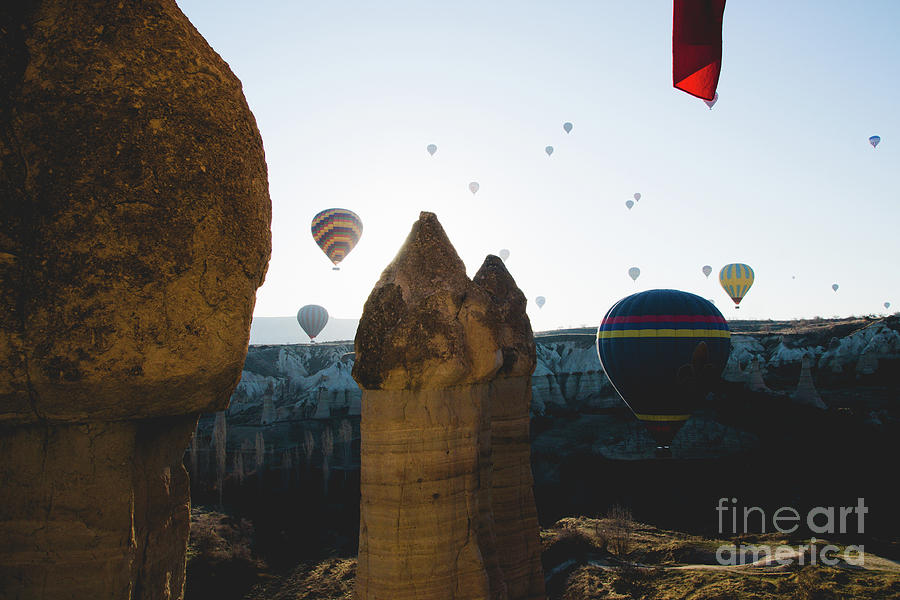 hot air balloons for tourists flying over rock formations at sunrise in the valley of Cappadocia. #4 Photograph by Joaquin Corbalan