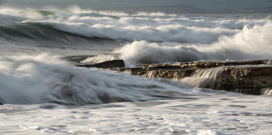 Rocky seashore with wavy ocean and waves crashing on the rocks  Photograph by Michalakis Ppalis