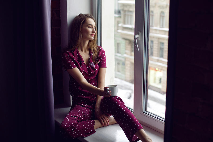Young Woman In Red Pajamas Sitting In The Morning On The Windowsill Photograph