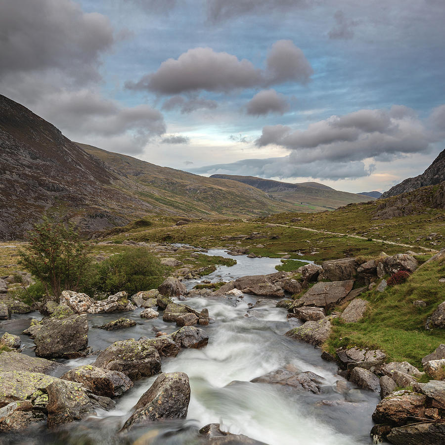 Moody landscape image of river flowing down mountain range near ...