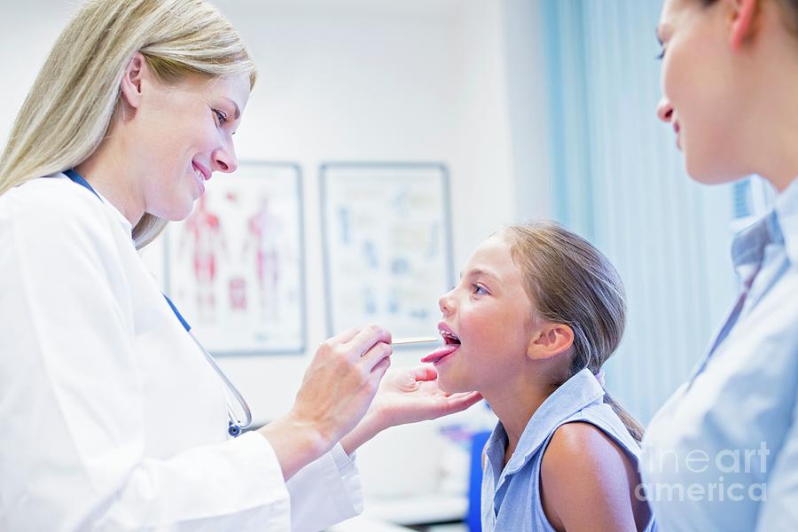 Doctor examining back of 8 year-old girl - Stock Image - C040/1357 -  Science Photo Library