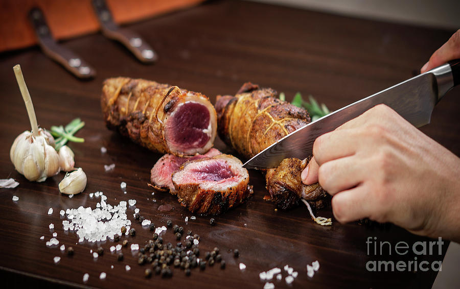 Slicing Organic Roast Beef Roll On Wood Table With Ingredients Photograph