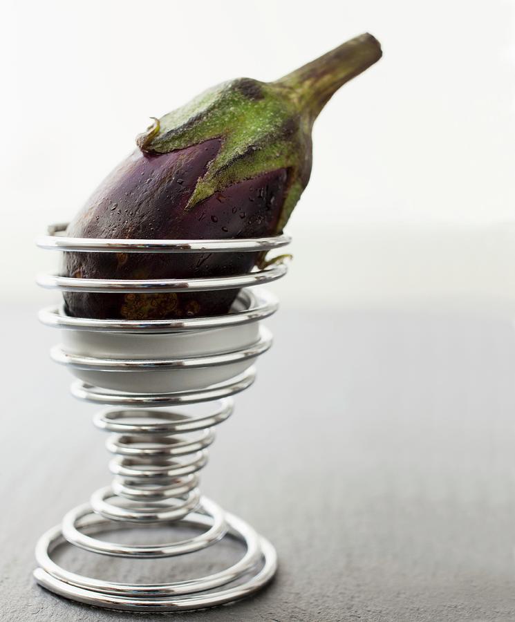 A Baby Aubergine In A Spiral Ice Cream Cone Holder Photograph by Katharine Pollak