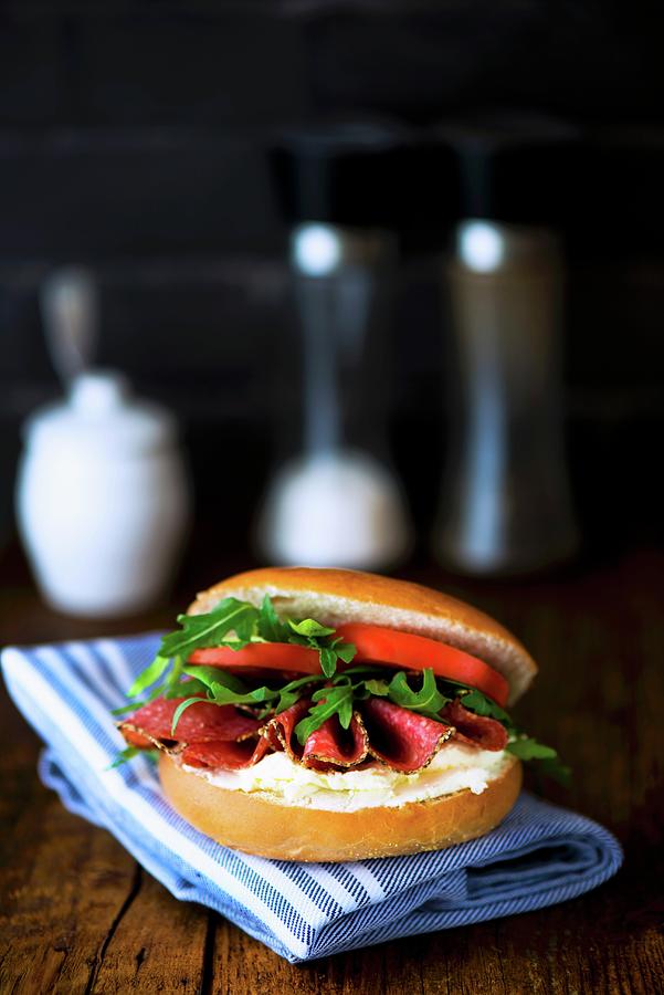 A Bagel With Cream Cheese, Pepper Salami, Rocket And Tomatoes Photograph by Jamie Watson