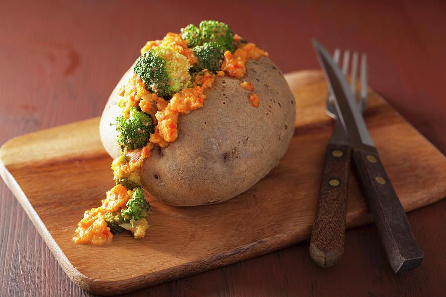 A Baked Potato With Broccoli And Vegan Cheese Sauce On A Chopping Board Photograph by Olga Miltsova