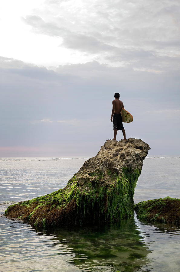 A Balinese Surfer Perched On Top Of A Photograph by Xpacifica