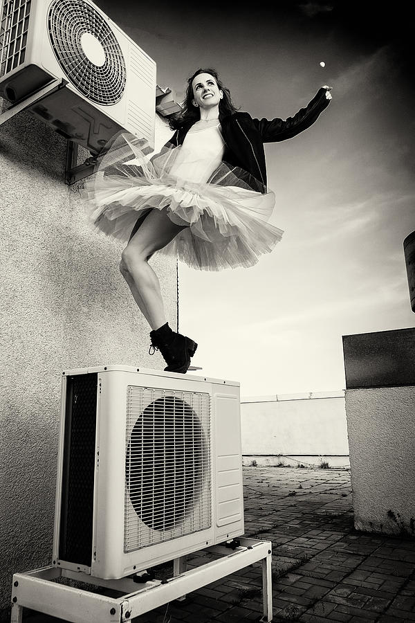 A Ballerina In Tutu, Jacket And Boots Climbed On The Air Conditioner And Poses Against The Sky Photograph by Alexandr