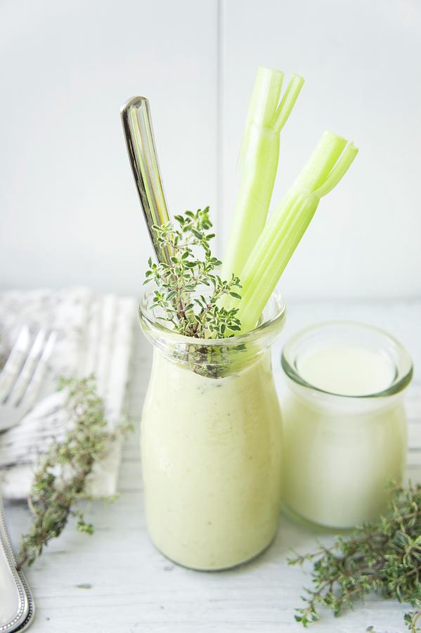A Banana And Avocado Smoothie Garnished With Celery Sticks And Thyme Photograph by Martina Schindler
