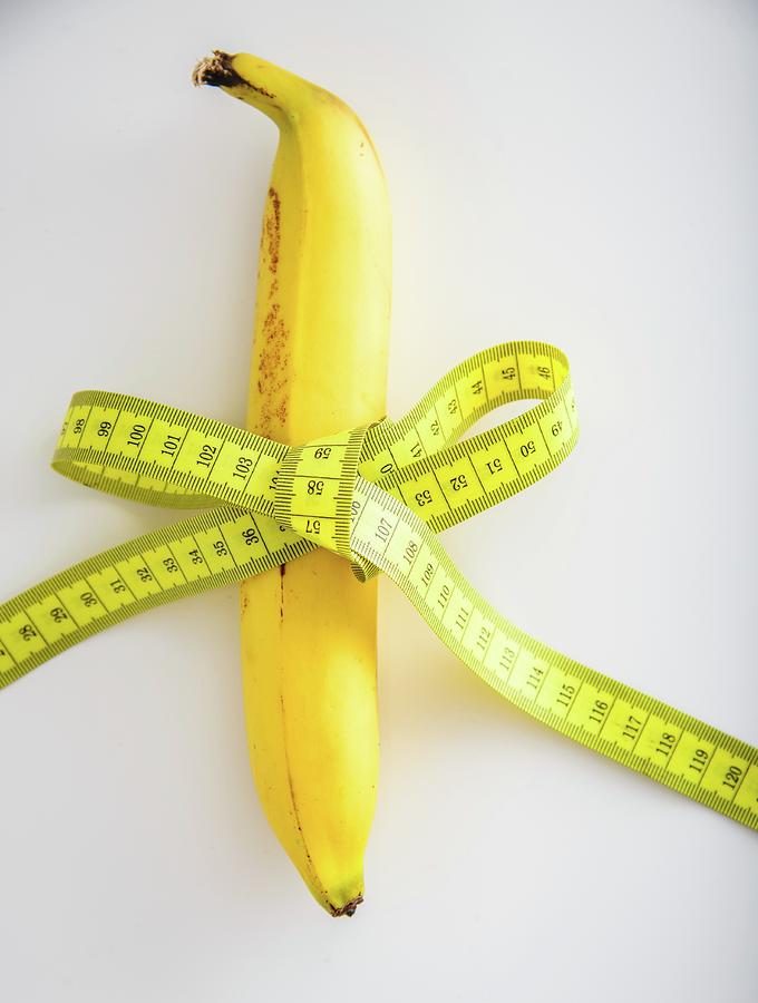 A Banana Tied With A Tape Measure On A White Surface Photograph by Katrin Benary