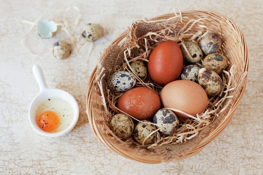 A Basket Of Quail And Hen Eggs With A Cracked Open Quails Egg Next To It Photograph by Jane Saunders