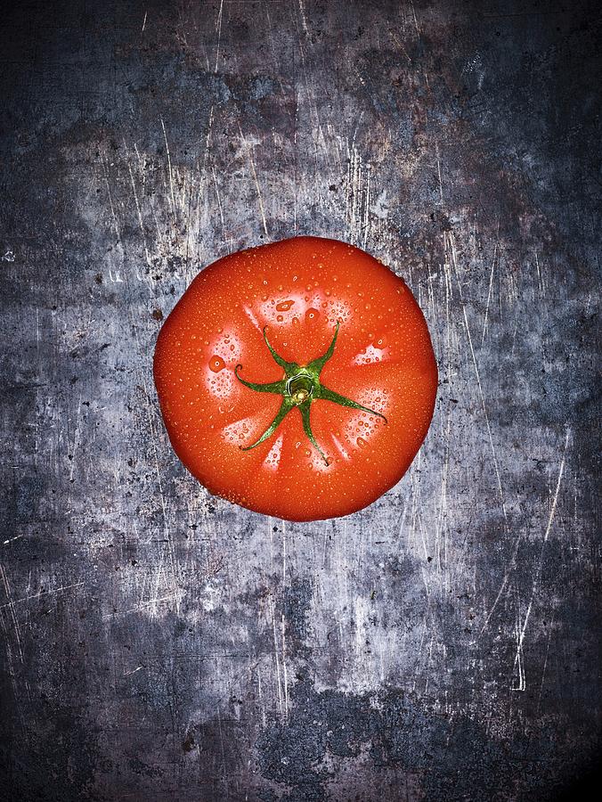 A Beef Tomato With Droplets Of Water On A Grey Surface seen From Above Photograph by Peter Rees