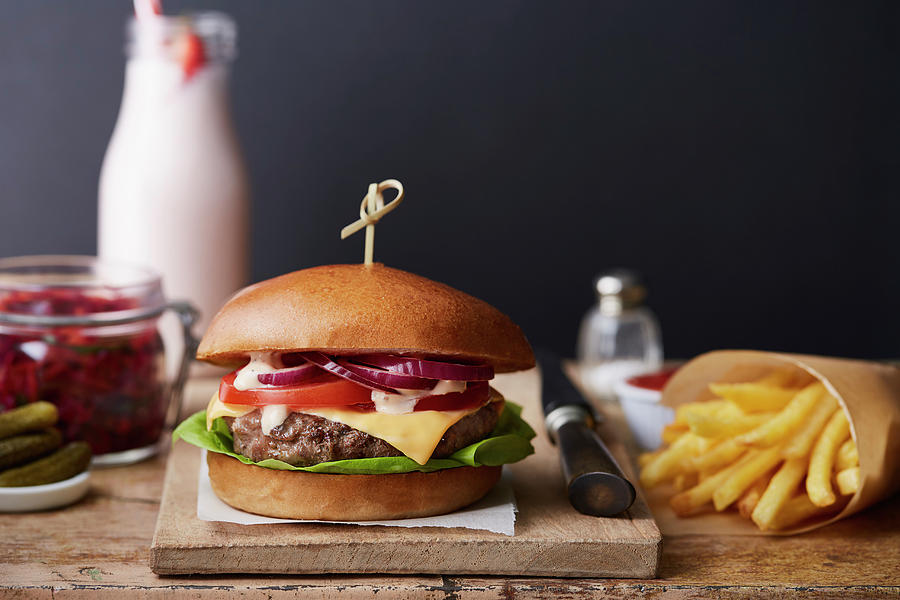 A Beefburger With Chips On A Wooden Chopping Board Photograph by Kathrin Mccrea