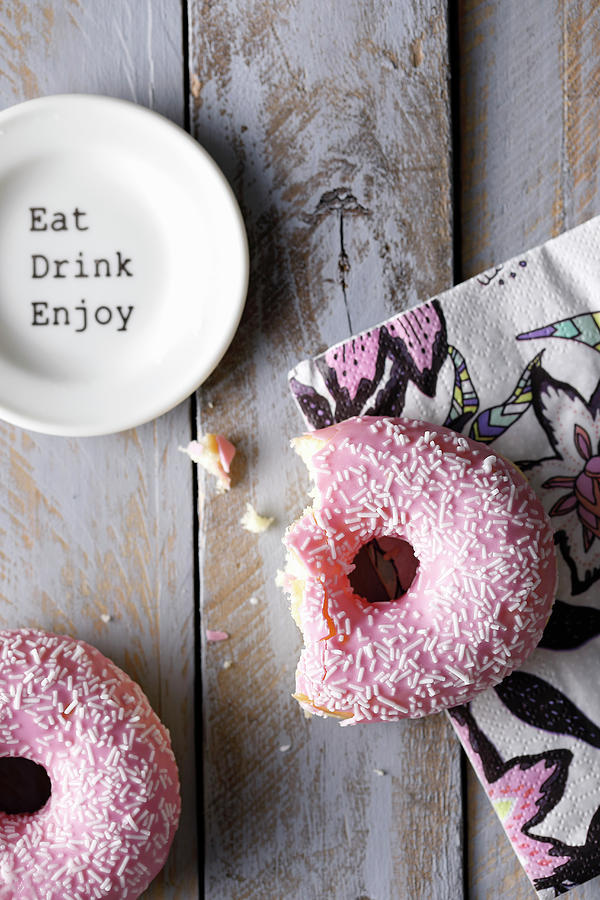 A Bitten Doughnut With Pink Frosting On A Colourful Napkin Photograph by Mona Binner Photographie