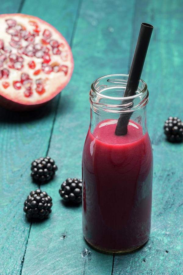 A Blackberry And Pomegranate Smoothie In A Bottle With A Straw Photograph by Nils Melzer