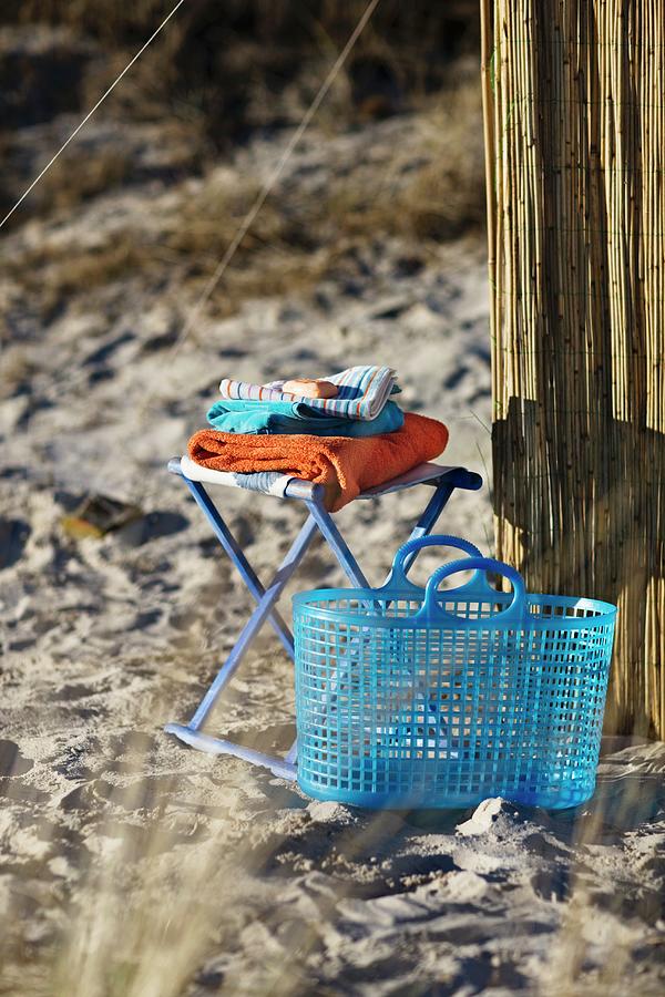 A Blue Plastic Basket Next To A Stool With Towel On A Sandy Beach Photograph by Per Magnus Persson