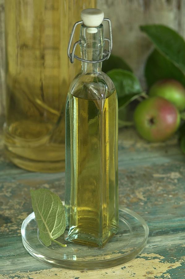 A Bottle Of Apple Vinegar And Apples In A Rustic Cupboard Niche Photograph by Achim Sass