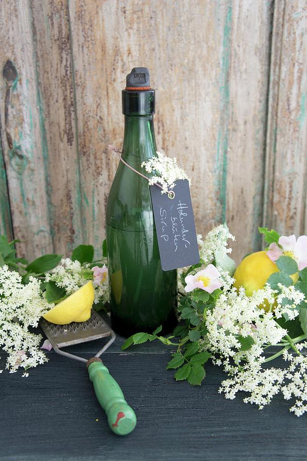 A Bottle Of Elderflower Syrup With Lemons Elderflowers And Briar Rose Photograph by Martina Schindler