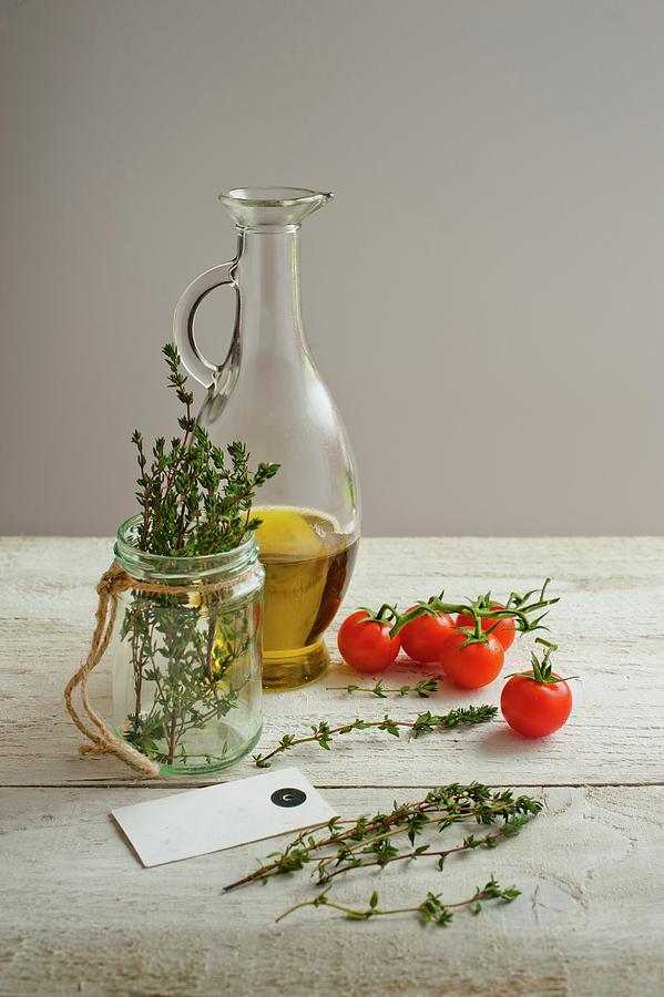 A Bottle Of Olive Oil, Thyme And Cherry Tomatoes On A Light Wooden Surface Photograph by Magdalena Hendey