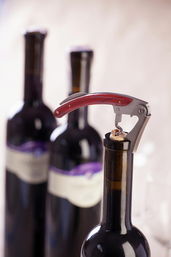 A Bottle Of Red Wine Being Opened With A Corkscrew Photograph by Studio Lipov