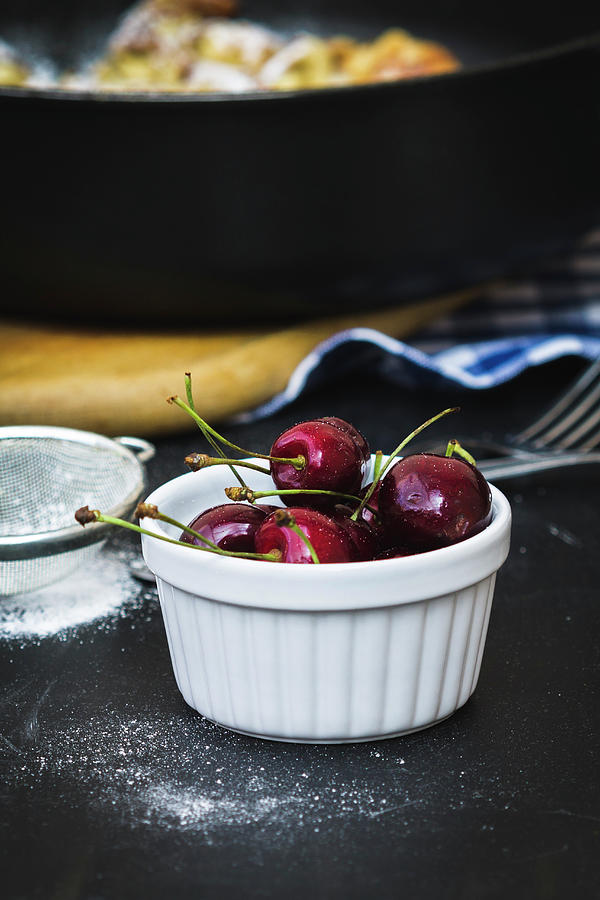 A Bowl Of Fresh Cherries Next To A Sieve Of Icing Sugar Photograph by Antonia Kurz