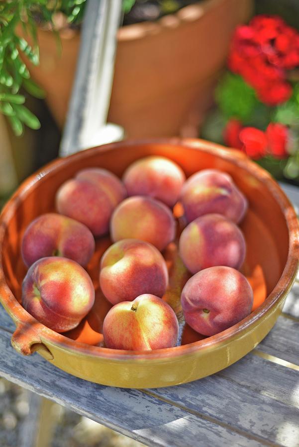 A Bowl Of Fresh Peaches On A Garden Chair Photograph by Roger Stowell