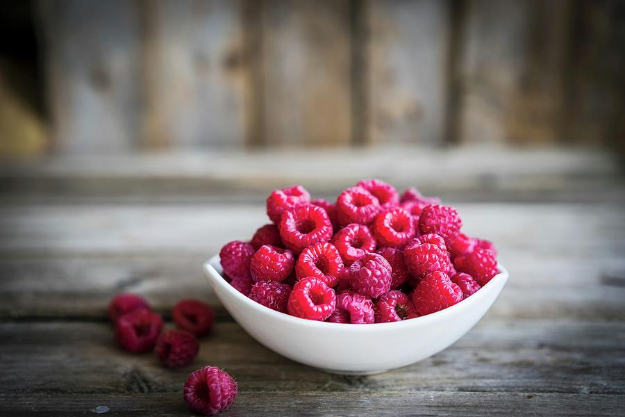 A Bowl Of Fresh Raspberries On A Rustic Wooden Surface Photograph by Alena Haurylik