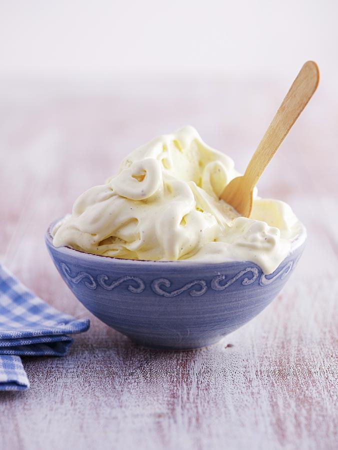 A Bowl Of Melting Vanilla Ice Cream With A Wooden Spoon Photograph by Brachat, Oliver