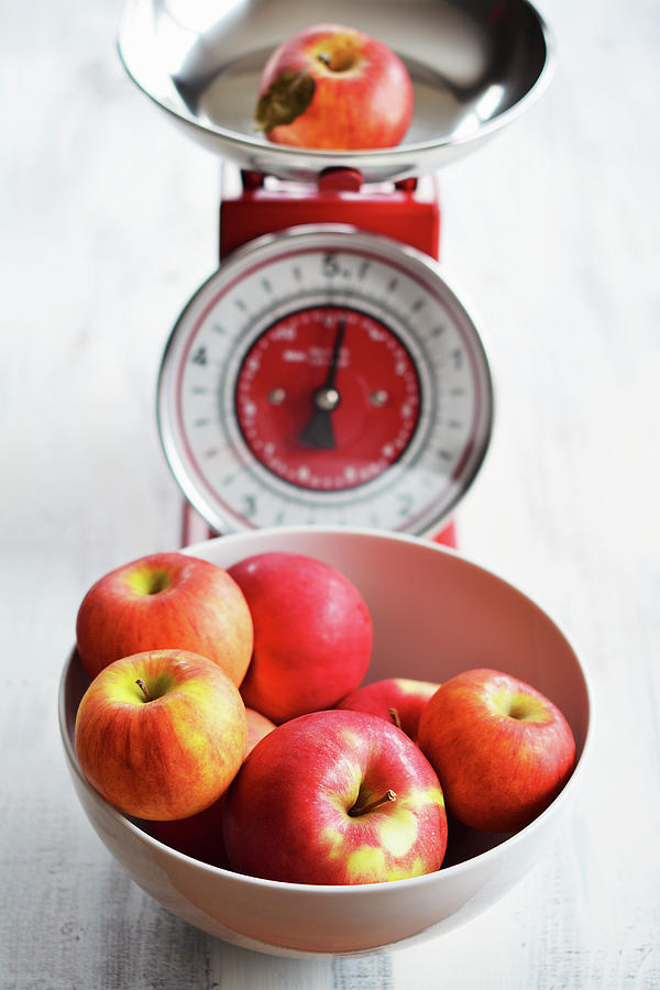 A Bowl Of Red Apples And One On An Old-fashioned Pair Of Kitchen Scales Photograph by Mariola Streim