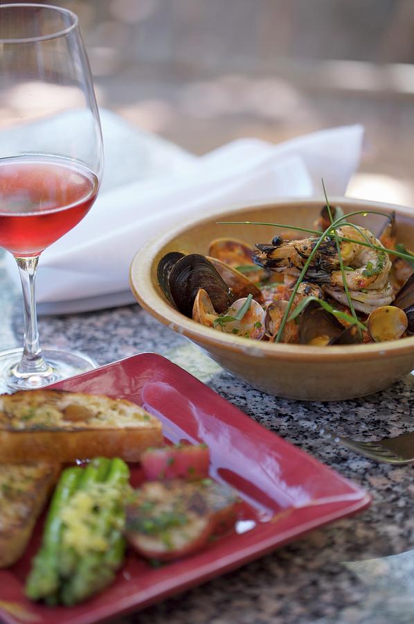 A Bowl Of Seafood Stew With A Glass Of Wine And A Plate Of Toasted Bread Photograph by Jennifer Martine
