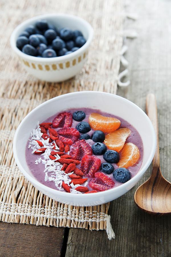 A Bowl Of Smoothie With Blueberries, Desiccated Coconut, Goji Berries, Raspberries And Clementines Photograph by Victoria Firmston