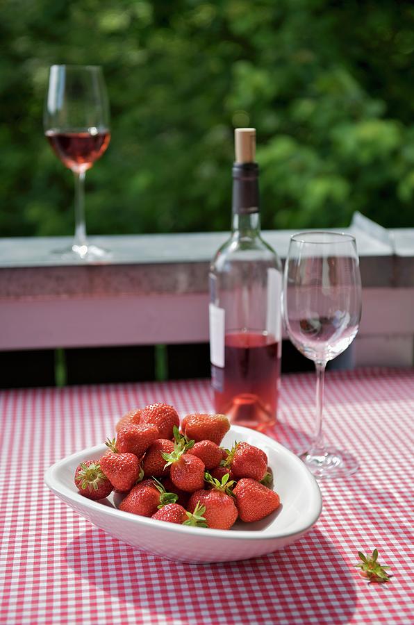 A Bowl Of Strawberries And Some Ros Wine On A Table On The Balcony, The Table Covered With A Gingham Tablecloth Photograph by Heinze, Winfried