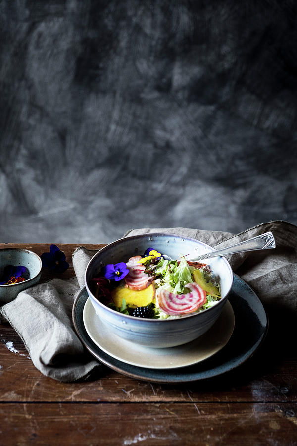 A Bowl With Salad And Eatable Flowers At A Wooden Table From The Side Photograph by Lucie Beck