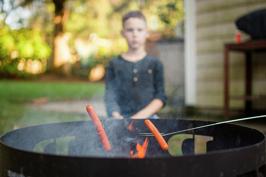 Summer Photograph - A Boy Roasting Hot Dogs With His Family On An Outdoor Fire Pit by Cavan Images