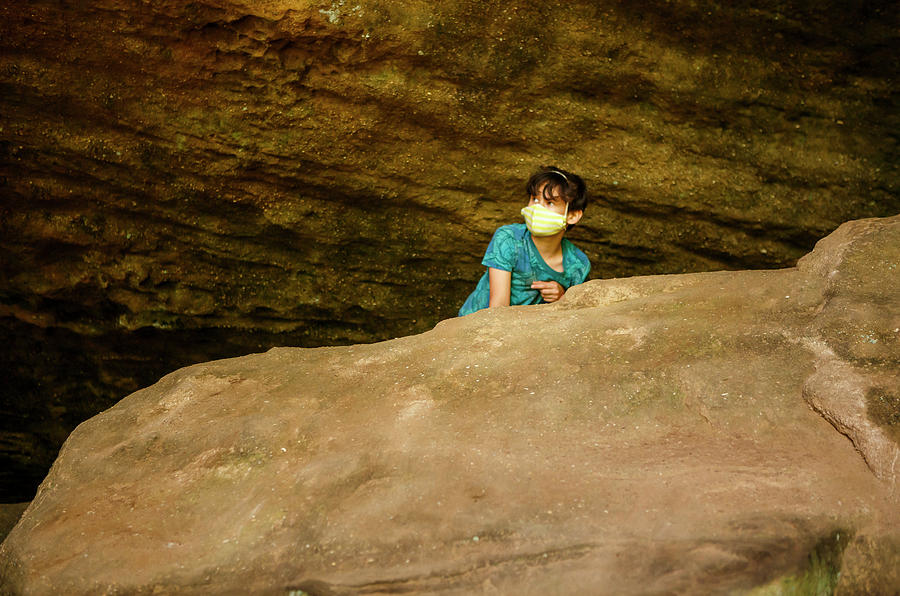 Nature Photograph - A Boy Wearing Face Masks Peers Over A Large Rock In A Sandstone Gorge by Cavan Images