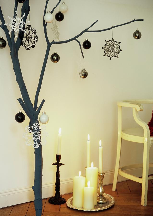 A Branch Decorated For Christmas Next To A Tray Of Candles Photograph by Julia Hoersch