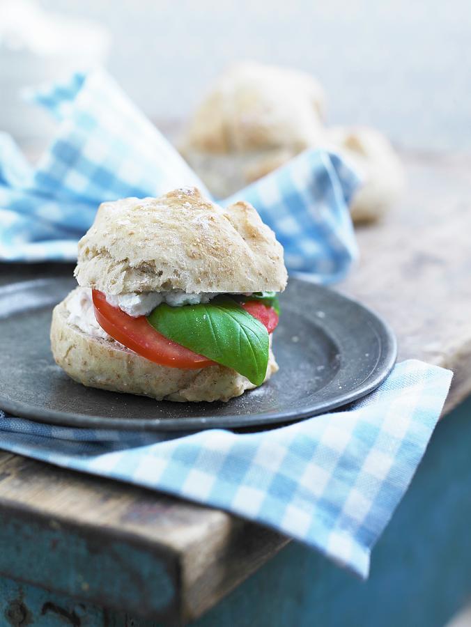 A Bread Roll With Fresh Cheese, Tomato And Basil Leaves Photograph by Mikkel Adsbl
