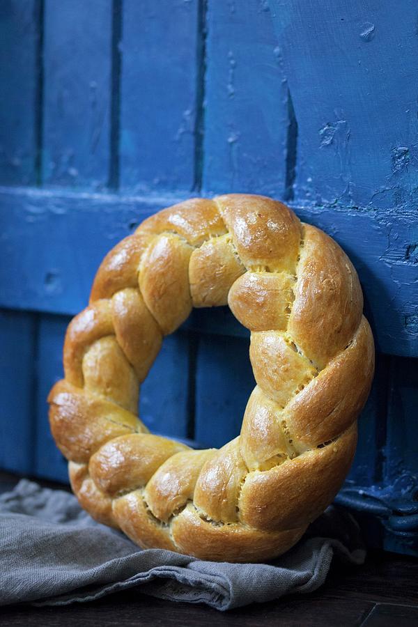 A Brioche Wreath Leaning Against A Blue Wooden Door Photograph by Julia Cawley