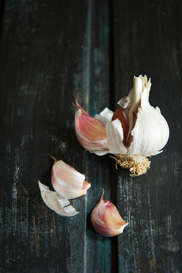 A Broken Garlic Bulb On A Black Wooden Surface Photograph by Patricia Miceli