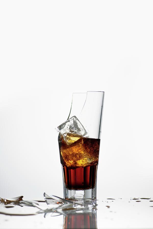 A Broken Glass With Cola And Ice Cubes Photograph by Feig & Feig
