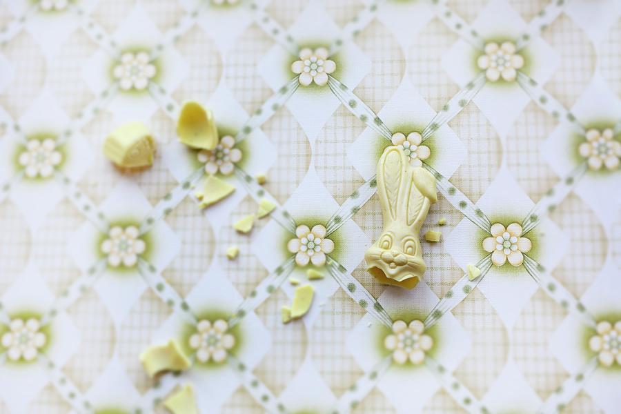 A Broken White Chocolate Bunny On A Vintage Surface Photograph by Sabine Lscher