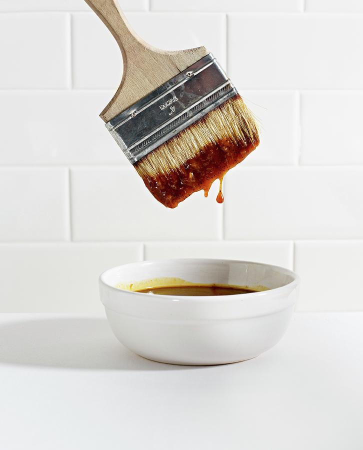 A Brush Being Dipped In A Bowl Of Barbecue Sauce Photograph by Clinton Hussey