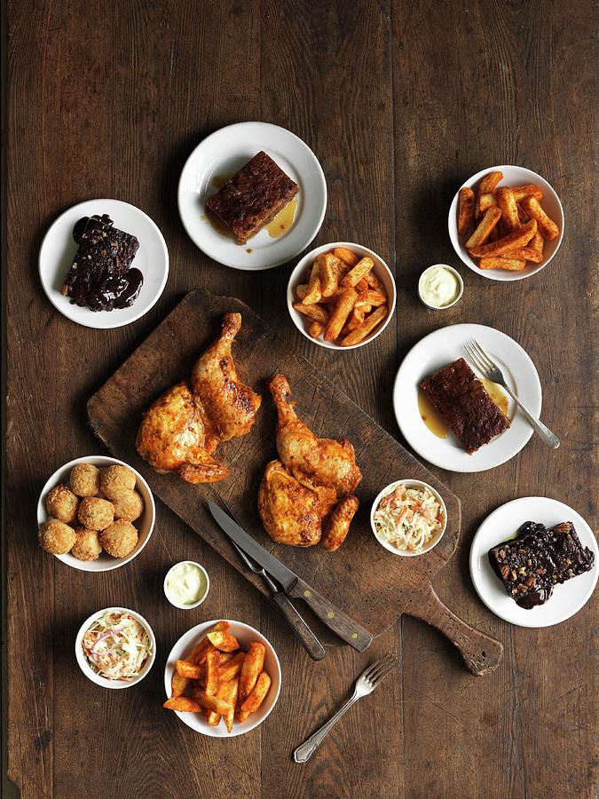 A Buffet Featuring Spicy Grilled Chicken, Rice Balls, Chips, Coleslaw, Brownies And Caramel Pudding Photograph by Jonathan Gregson