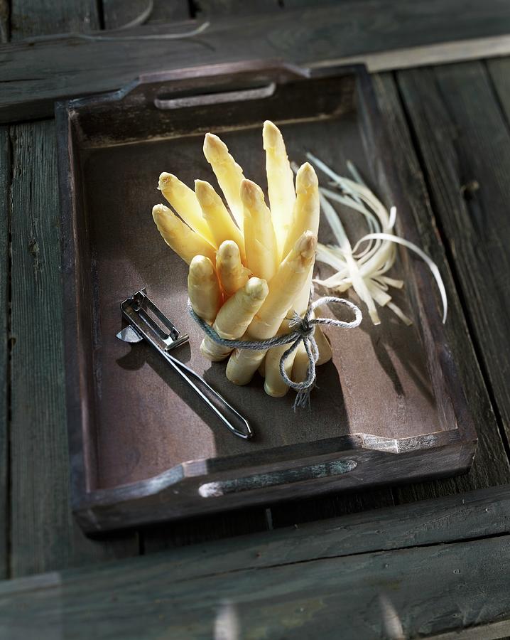 A Bunch Of White Asparagus With A Peeler On A Wooden Tray Photograph by Hebra
