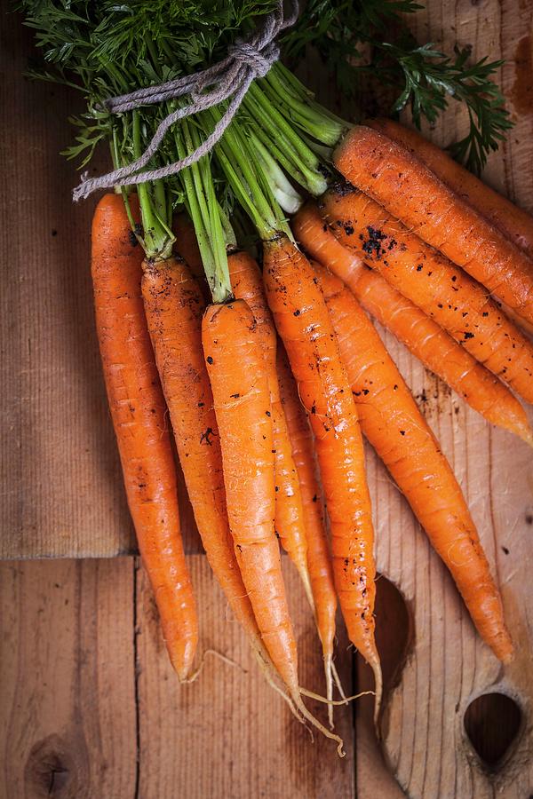 A Bundle Of Fresh Carrots On A Wooden Board Photograph by Elisabeth Von Plnitz-eisfeld