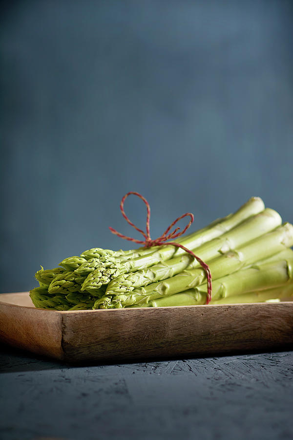 A Bundle Of Green Asparagus On A Wooden Dish Photograph by Christoph Maria Hnting