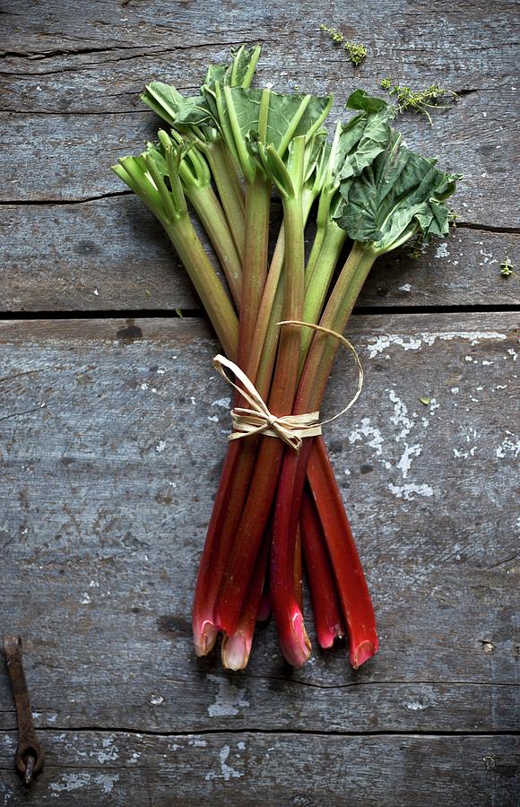 A Bundle Of Rhubarb On A Rustic Wooden Board Photograph by Denise Rene Schuster