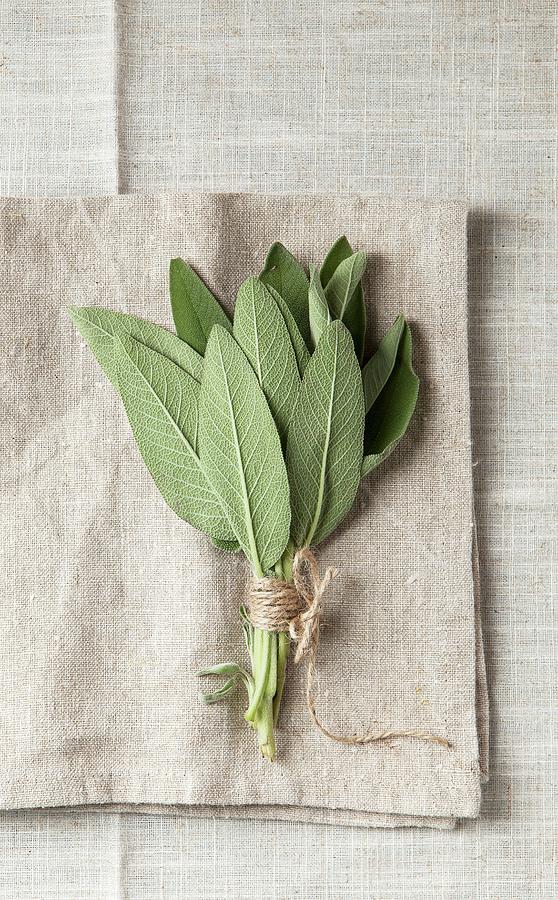 A Bundle Of Sage On A Grey, Coarse Linen Napkin Photograph by Stacy Grant