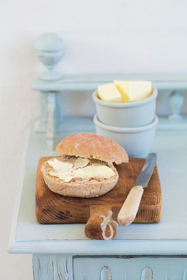 A Buttered Roll With A Knife On A Rustic Wooden Board Photograph by Elisabeth Clfen