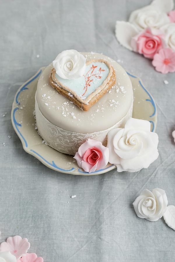 A Cake Decorated With Fondant Icing, A Heart-shaped Biscuit And Sugar Roses Photograph by Mandy Reschke